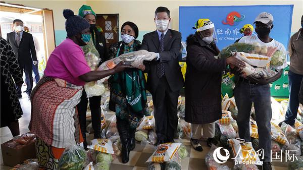 李南代办和德拉米尼主席向当地贫困代表分发食品包。人民网 刘畅 摄